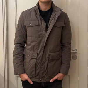 Massimo dutti jacka - Snygg brun parkajacka från Massimo dutti med flera fickor framtill, hög krage och dragkedja med tryckknappar. Jackan har ett ljust lila foder och är perfekt för höst och vinter, med normal passform och långärmade ärmar. En knapp saknas, de sista bilden. Annars mycket bra skick! Pris kan diskuteras 