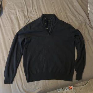 Mörkblå polotröja Massimo Dutti - Snygg mörkblå polotröja från Massimo Dutti i mjuk bomull och kashmirmix. Tröjan har ribbad krage med knappar och långärmad passform. Perfekt för dig som gillar stilrena och klassiska plagg med lite extra premiumkänsla.