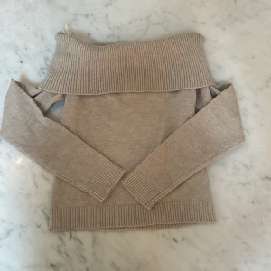 Beige offshoulder stickad tröja Gina Tricot - Superfin beige stickad tröja från Gina Tricot med bred ribbad kant och offshoulder-design. Tröjan har långa ärmar och är perfekt för dig som gillar en chill men ändå snygg stil. Passar grymt till både jeans och kjol.