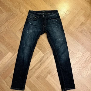 Jack & Jones Slim Glenn jeans mörkblå - Snygga Slim Glenn jeans från Jack & Jones i mörkblå tvätt med slitningar och coola detaljer. Modellen har fem fickor, normal passform och klassisk knappgylf. Perfekt för dig som gillar en modern och stilren look. Hör av er vid frågor eller intresse 