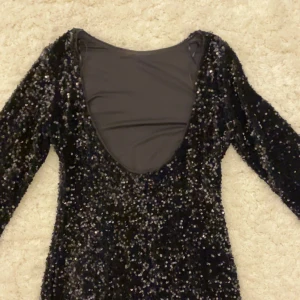 Svart glitter klänning H&M - En kort långärmad svart paljett klänning med öppen rygg från H&M! Aldrig använd💕