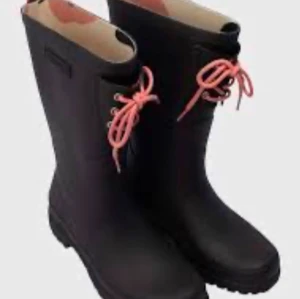 Svarta Tretorn stövlar med rosa snörning - Svarta stövlar från Tretorn med snygga rosa snören framtill och rosa detaljer baktill. Tillverkade i slitstark syntet med grov sula och rund tå. Perfekta för regniga dagar och outdoor vibes.