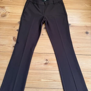 Low waist Vera kostymbyxor  - Snygga low waist bruna Vera kostymbyxor från Bik Bok med utsvängda ben. Byxorna har bälteshällor, framfickor och diskreta bakfickor. Stängs med dragkedja och knapp framtill. Perfekt för en clean och stilren look. I storlek S! Mycket bra skick!