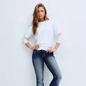 Blå bootcut jeans med mellanblå tvätt - Säljer ett par snygga blå bootcut jeans med klassisk femficksdesign och mellanblå tvätt. Jeansen har en lätt utsvängd passform nertill och subtila slitningar framtill för en cool look. Perfekta till sneakers eller boots och passar dig som gillar en tidlös stil.