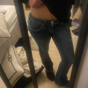 Rock Revival lågmidjade bootcut jeans - Säljer ett par lågmidjade utsvängda blå jeans från Rock Revival med snygga kontrastsömmar och broderade detaljer på fickorna. Passar mig perfekt som brukar ha 32,34 i jeans och är ca 165cm lång. Köppta för 2500 i butik❣️❣️