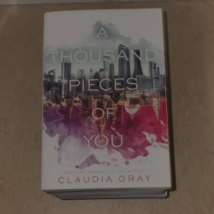 A Thousand Pieces of You - En snygg och spännande bok med ett färgstarkt omslag som lockar till läsning. Perfekt för dig som gillar äventyr och mysterier i urbana miljöer. Skriven av New York Times-bästsäljande författaren Claudia Gray.