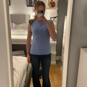 Ljusblå ärmlös topp från 157 - Säljer en ljusblå, enkel och stilren topp från 157 i storlek XS. Toppen är ärmlös med rund hals och har en slim passform som sitter snyggt mot kroppen. 