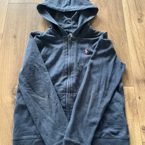 Mörkblå hoodie från Polo Ralph Lauren - Hej! Jag säljer min Ralph Laurent den är helt ny har aldrig användt den typ och den är för 14 till 16 år gammal. Skriv till mig vid frågor om tröjan.