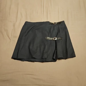 Mörkblå kortkjol med bältesdetaljer från Brandy Melville - ❗️Skriv innan köp❗️Mörkblå kortkjol från Brandy Melville med två bältesdetaljer i midjan och på sidan. Kjolen har en enkel fin design. Har använts ett fåtal ggr.