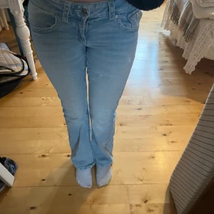 Bootcut jeans i ljusblå denim Gina Tricot Young  - Snygga bootcut jeans från Gina Tricot i ljusblå tvättad denim. Klassisk femficksmodell med knapp och dragkedja fram. Jeansen har en lätt utsvängd passform nedtill och normal midja. Jag är ca 149 cm och är bra längd för mig.