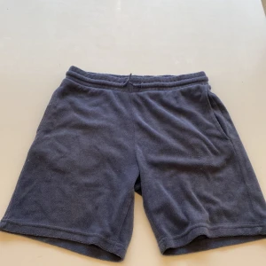 Mörkblå frottéshorts från 157 - Mysiga mörkblå shorts från 157 i mjukt frottématerial. De har elastisk midja och en loose passform, perfekta för chill dagar. Klassisk enkel design utan mönster eller extra detaljer. Snygga att matcha med en hoodie eller t-shirt.