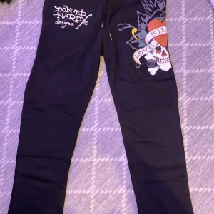 Svarta Ed Hardy mjukisbyxor M - Svarta mjukisbyxor från Ed Hardy med coolt tryck på ena benet med döskalle, hjärta och texten 'Love Kills'. Snyggt Ed Hardy-tryck både fram och bak. Byxorna har snörning i midjan och är gjorda i mjukt material för skön passform. Köptes i USA🤟🏽🤟🏽