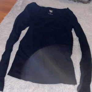 Svart långärmad tröja från 157 - En enkel svart långärmad tröja från 157, perfekt för dig som gillar stilrena och basic plagg. Tröjan har rund hals och är gjord i mjuk bomull som känns skön mot huden. Passformen är normal och funkar till många olika outfits.