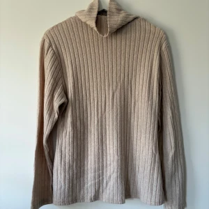 Beige ribbad polotröja från SHEIN - Säljer en beige polotröja från SHEIN Curve i storlek 0XL. Tröjan har ett ribbat mönster och är långärmad med en hög krage. Perfekt för dig som gillar en chill och enkel stil med lite extra cozy känsla.