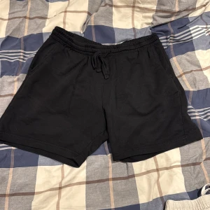 Svarta shorts från H&M med snörning - Svarta shorts från H&M i regular fit med elastisk midja och snörning. Mjukt bomullsmaterial, två sidofickor fram och en bakficka. Perfekta för chill dagar eller träning. Klassisk och enkel design som funkar till det mesta.