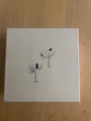 Apple AirPods Pro 2 - Säljer ett par vita Apple AirPods Pro 2 med stilren design och silikonproppar för bästa passform. De har aktiv brusreducering, transparensläge och adaptiv ljudkontroll. Perfekta för musik, samtal och träning. Kommer i originalförpackning.