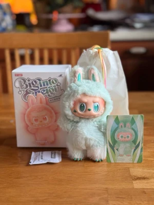 Pop Mart The Monsters Labubu Big into Energy Serenity - Söt samlarfigur från BigMoe Design x Pop Mart, föreställande en karaktär i en fluffig mintgrön och vit kanindräkt med rosa detaljer. Kommer med originalförpackning, samlarkort och tygpåse. Perfekt för dig som gillar unika designer och kawaii-stil.