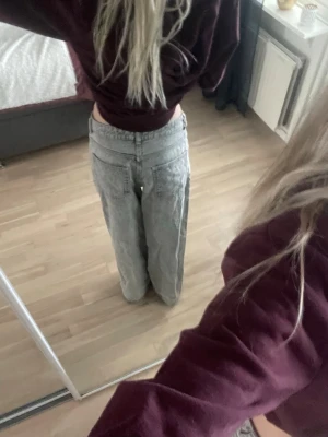 Vida ljusgrå jeans - Säljer ett par ljusgrå jeans med raka, vida ben. Jeansen har klassisk femficksmodell och stängs med knapp och dragkedja. Perfekta för en avslappnad och trendig look.