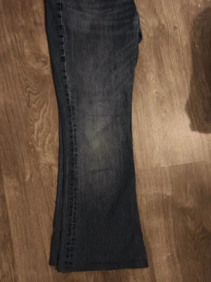 Blå bootcut jeans från Levis - Snygga blå bootcut jeans från Levis med klassisk femficksdesign och låg midja. Jeansen har en lätt tvättad look och är tillverkade i mjukt denimtyg som ger en avslappnad vibe. Perfekta för dig som gillar en retrostil med lite utsvängda ben.