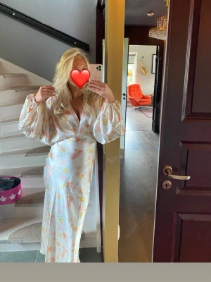 Lång klänning satin - Såå fin långklänning i ljus satin med blommigt mönster i pastellfärger. Omlottmodell och vida långärmar 😇💕