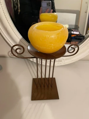 Rostbrun ljushållare i metall - Säljer en dekorativ ljushållare i rostbrun metall med spiralformade detaljer på sidorna och fyrkantig fot. Passar perfekt för blockljus eller större värmeljus. Ger en rustik känsla till rummet och funkar som snygg inredningsdetalj.