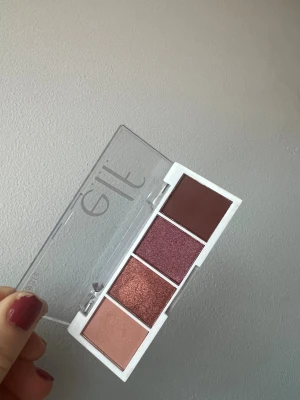 Ögonskuggspalett ELF - Snygg ögonskuggspalett från Elf med fyra nyanser i rosé, koppar, vinrött och matt brun. Paletten har både skimriga och matta skuggor i ett smidigt vitt plastetui med genomskinligt lock. Perfekt för kreativa ögonlooks och enkel att ta med i väskan. Endast testad.