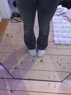 Grå bootcut jeans med hög midja - Snygga grå bootcut jeans med hög midja och klassiska bakfickor. Jeansen har en lätt utsvängd passform nedtill och är perfekta för en trendig och avslappnad look. Materialet är denim som ger en skön känsla och sitter snyggt på kroppen.