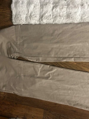 Beige chinos med rak passform - Snygga beige chinos med rak passform och klassisk design. Tillverkade i ett mjukt bomullstyg som känns bekvämt mot huden. Perfekta för dig som gillar en clean och enkel stil. Passar till det mesta och är lätta att matcha med olika plagg. Lite knottrig mellan benen annars fint skick