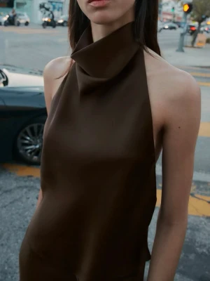 Satin topp  - Säljer en stilren brun klänning i halterneck-modell med hög krage och öppen rygg. Klänningen är ärmlös och har en slät, elegant finish som ger en modern look. Perfekt för dig som gillar minimalistisk stil. Pris kan diskuteras💕