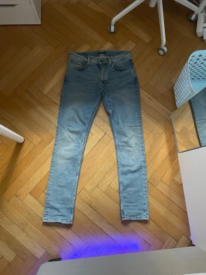 Ljusblå nudie jeans - Säljer ett par ljusblå jeans med klassisk femficksdesign och normal midja. Perfekta för en avslappnad och stilren look. Grimtim. Storleken är 31 32. Pris kan diskuteras.