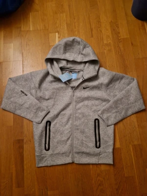 Grå nike tech nocta - Säljer en helt ny nike tech nocta! Storleken står XL men passar M!
