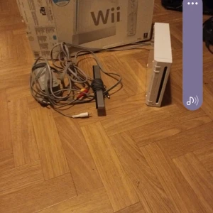 Nintendo Wii med tillbehör och spel - Nintendo Wii i vitt med originalkartong, två Wii-fjärrkontroller, nunchuk, sensorbar, kablar och fyra populära spel: Monsters vs Aliens, Spider-Man, Mario & Sonic at the Olympic Games och Wii Sports Resort. 