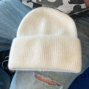 Mössa - Snygg och enkel vit mössa med ribbad struktur och bred uppvikt kant. Perfekt för kalla dagar och passar till alla stilar. Mjuk och skön stickad känsla som håller dig varm hela vintern.