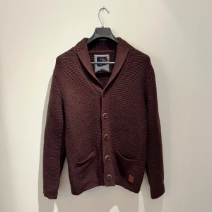 Brun stickad kofta från Redgreen - Mysig brun stickad kofta från Redgreen med snygga knappar framtill, två fickor och schyssta armbågslappar i manchester. Perfekt för lager-på-lager och chill höst- eller vinterstil. Dansk design med klassisk känsla. Hör av er vid frågor eller fler bilder