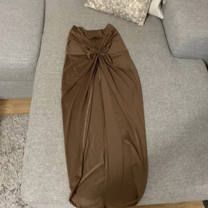 Brun kjol med topp st.36-38 stretch elegant  - Brun kjol med en knutdetalj framtill och en slits.  Brun kjol med en knutdetalj framtill och en slits.den har även en topp ska ta nya bilder snart.tror den är oanvänd. Jätte fin elegant mycket bra skick.storlek passar 36-38 stretch material .vet inte märke på den. 