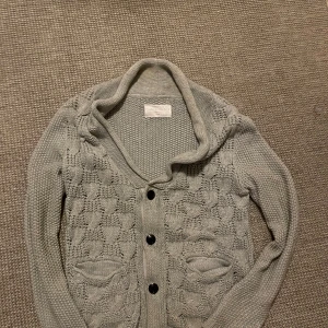 Grå kofta från These Glory Days - Säljer en stilren grå kofta från These Glory Days. Koftan har ett snyggt stickat mönster och knappar framtill. Perfekt för kyliga dagar och ger en mysig känsla. Passar bra till både jeans och kjol. Mycket bra skick, pyttelite missfärgning i kragen men ingenting som syns🙌 Skriv vid funderingar!