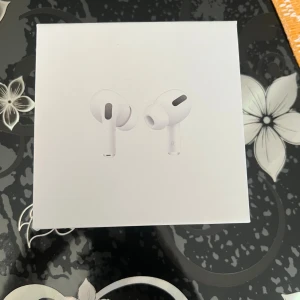 AirPods Pro - Apple AirPods Pro i originalförpackning med laddningsetui, extra öronproppar, laddkabel och manualer. Allt ser komplett och i mycket fint skick ut, perfekt för dig som vill ha trådlösa hörlurar med aktiv brusreducering och hög ljudkvalitet. Helt nya.