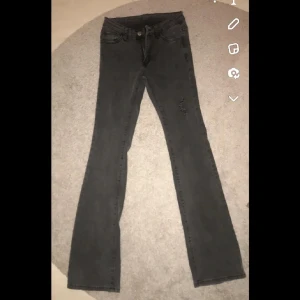 Grå raka jeans - Gråa jeans med klassisk femficksdesign och rak passform. Jeansen har en enkel look med diskret slitning på ena benet och är tillverkade i ett mjukt denimtyg. Perfekta för dig som gillar en stilren och tidlös vibe.