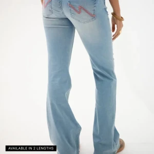 Ljusblå bootcut jeans med rosa söm - Snygga ljusblå jeans med bootcut passform och hög midja. Jeansen har coola rosa broderade sömmar på bakfickorna och silverfärgade knappar framtill. Tillverkade i mjukt denim-material som sitter skönt och ger en fräsch look.