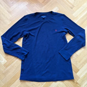 Marinblå långärmad tröja Polo Ralph Lauren - Säljer en marinblå långärmad tröja från Polo Ralph Lauren. Tröjan är i bomull med ett diskret rutmönster i strukturen och har det klassiska röda Polo-logot broderat på bröstet.  •Fraktar inom 24h!📦