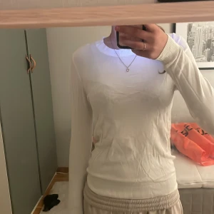 Vit stickad tröja från 157 - Vit, tunn stickad tröja från Lager 157 med rund halsringning och långa ärmar. Tröjan har ribbade muddar vid ärmslut och nederkant, vilket ger en snygg och enkel look. Säljer pga kommer inte till användning 
