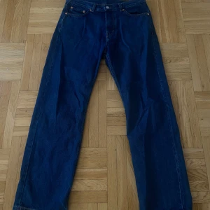 Weekday jeans - Klassiska WEEKDAY jeans i mörkblå denim med raka ben och femficksmodell. Jeansen har normal midja och knäppning fram. Perfekta för dig som gillar en tidlös och avslappnad stil. Den är i storlek/längd 30/30. S/M.
