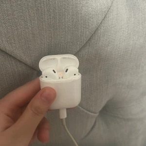 AirPods 2 - Apple AirPods 2 med laddningsetui. Trådlösa hörlurar med smidig laddning via Lightning-kabel. Fungerar med iPhone och andra Apple-enheter. Mindre repor och normalt slitage på etuiet, men i gott skick och fullt fungerande.