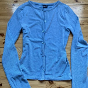 Ljusblå kofta från Gina Tricot XS - Supersöt ljusblå kofta från Gina Tricot i storlek XS. Den har långa ärmar, rund halsringning och knäppning med matchande knappar framtill. Perfekt att slänga över en topp för en chill look. Materialet är mjukt och känns skönt mot huden.