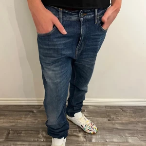 Blå jeans Pistolero 31/34 loose fit - Säljer ett par blå jeans från Pistolero i modellen loose fit. Jeansen har klassisk femficksdesign, snygga slitningar och kontrastsömmar. Tillverkade i bomull med en rak och avslappnad passform. Perfekta för dig som gillar en chill och bekväm stil.