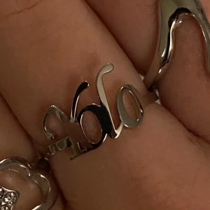 Silver ring Yolo - Säljer en silvrig ring med texten 'yolo' i snyggt, böljande typsnitt. Ringen är öppen baktill vilket gör den justerbar och passar flera storlekar. Perfekt accessoar för dig som vill sticka ut och visa din personlighet. Köpt från skyice