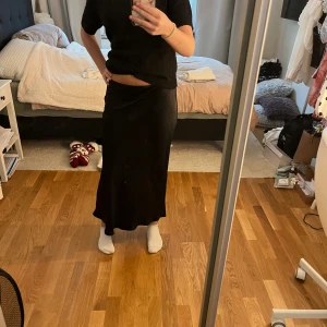 Svart satin långkjol - Säljer en svart långkjol från DW Icons i storlek M. Helt ny💕Passar även från S