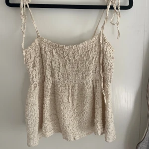Beige linnetopp med knytband XS - Supersöt beige linnetopp med smockad struktur och tunna axelband som knyts.