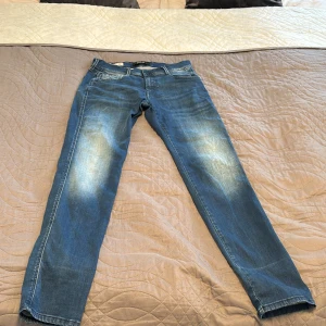 Blå Replay jeans, midwaist, 30/32 - Snygga blå jeans från Replay i klassisk tvätt med slitningar på låren. Modellen har raka ben och normal passform, midwaist och femficksdesign. Perfekta för dig som gillar en enkel men stilren look. Materialet är klassisk jeansbomull.
