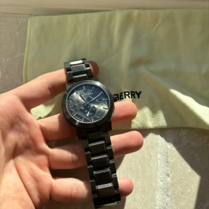 Burberry klocka - Helt brutalt snygg unik Burberry klocka i borstat mörkt stål som glänser på armen. Sweishiskt urverk och en super klocka som ligger på upp emot 10 000 kr ny. Självklart äkta och tveka inte vid minsta fundering!